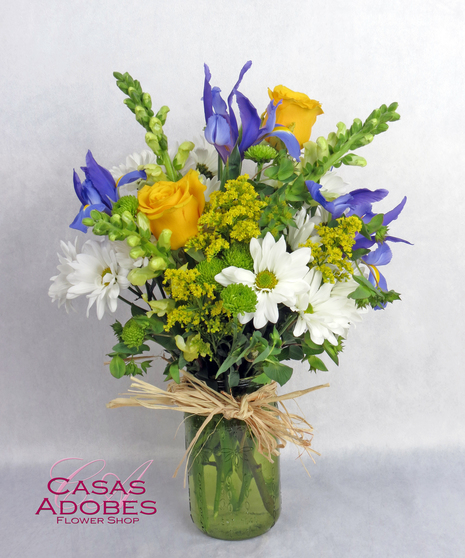 green mason jar vase with iris, yellow roses, and white daisies