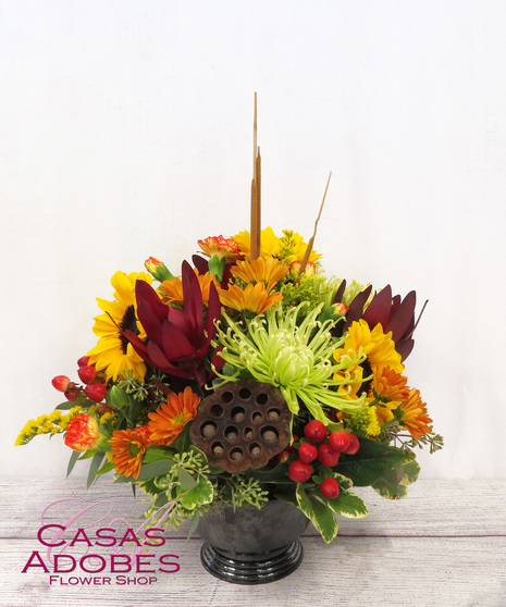 Bright Autumn Flowers in a Compote Container with green mums, bronze daisies, sunflowers, berries and mini carnations.