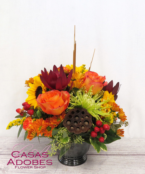 Bright Autumn Flowers in a Compote Container with green mums, bronze daisies, sunflowers, berries and mini carnations.