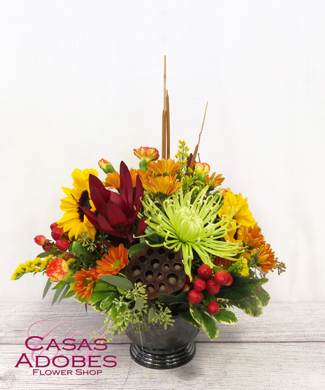 Bright Autumn Flowers in a Compote Container with green mums, bronze daisies, sunflowers, berries and mini carnations.