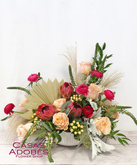 white ceramic pot with protea, peach garden roses, hot pink ranunculus, sweet william and dusty miler with berries and pampas grass