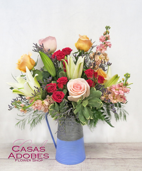 Galvanized pitcher with pink roses, hot pink spray roses, peach roses, peach stock and white lilies