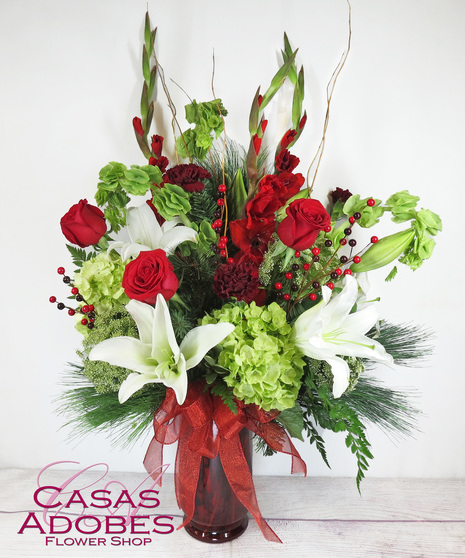 Vase with green hydrangea, red roses, white lily and berries with a red bow