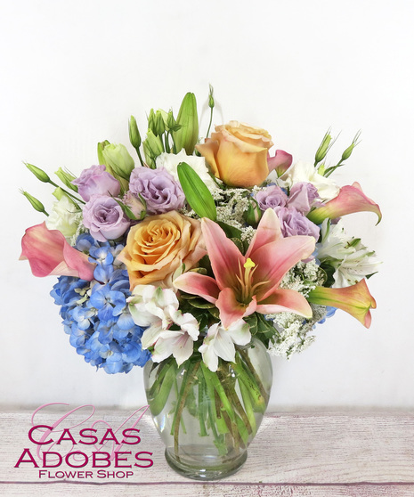 vase with blue hydrangea, pink calla lilies, peach roses, white alstroemeria and lisianthus
