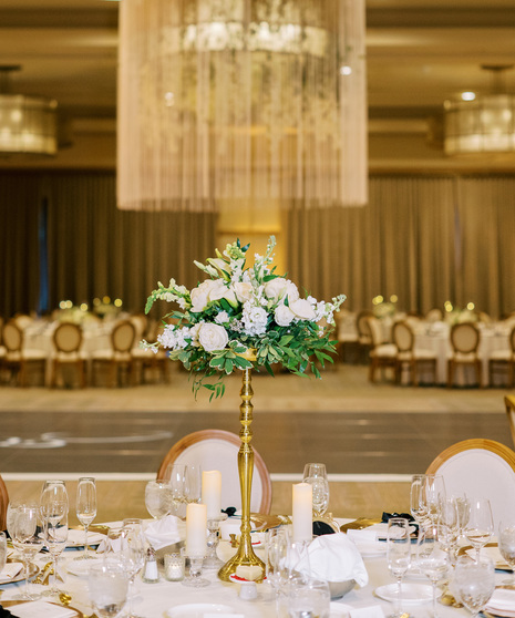  centerpiece featuring peonies, white roses, white miniature calla lilies, white lisianthus, white stock, and filled with greenery. 