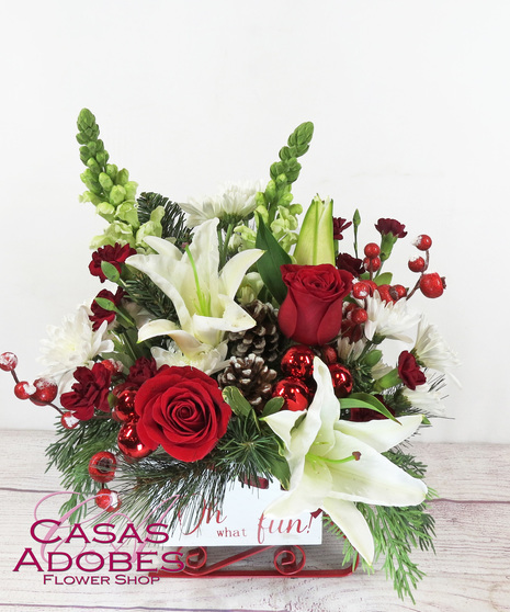 Sleigh with red roses, white lily, white snapdragons, pine cones, berries, winter greens