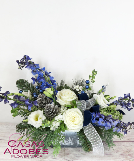 Snowy pine planter with white roses, white lisianthus, blue delphinium, pine cones, winter greens and velvet and silver ribbon