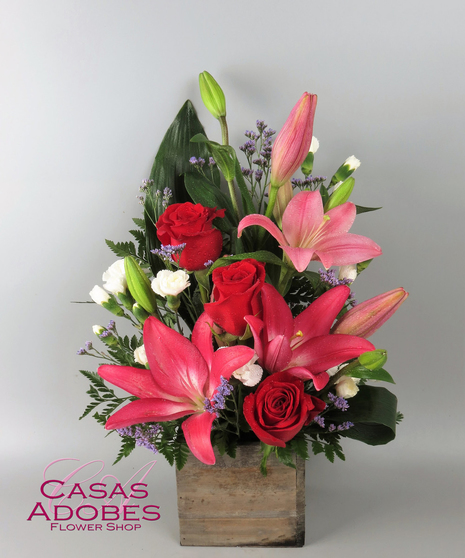 Pink Lily, red roses, and purple accent flowers in a wooden box 