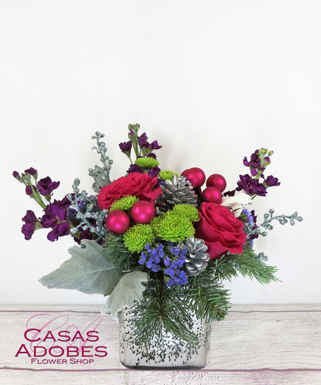 Mercury silver vase with bright hot pink roses, purple stock, green button mums, silver pine cones and berries and pink ornaments