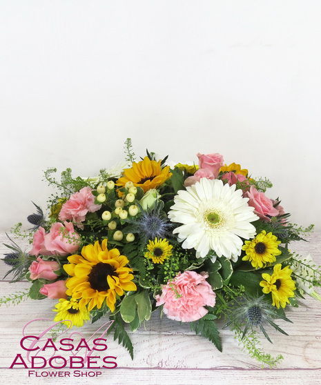 Low and lush centerpiece with sunflowers, snapdragons, gerbera daisies, carnations, lilies and solid aster