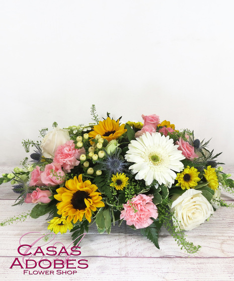 Low and lush centerpiece with sunflowers, snapdragons, gerbera daisies, carnations, lilies and solid aster